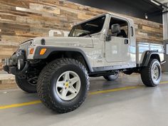 a white jeep parked in a garage next to wooden planks on the side of a building