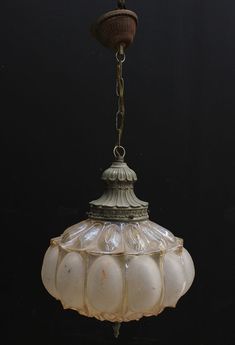 an old fashioned light fixture hanging from a chain on a black background with no one around it