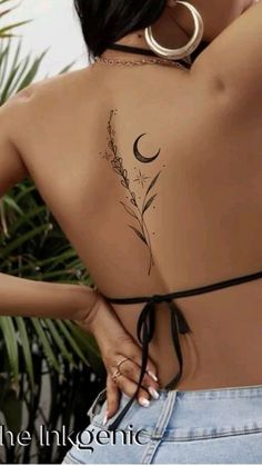 the back of a woman's body with tattoos on her shoulder and chest, in front of a palm tree