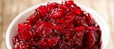 a white bowl filled with cranberry sauce on top of a wooden table