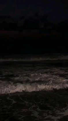 a person standing in the ocean at night