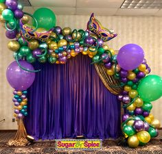 a purple and green mardi gras backdrop with balloons