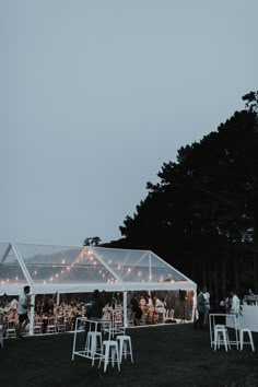 an outdoor tent set up with white chairs and string lights