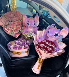 flowers and stuffed animals are in the back of a car with other items on it