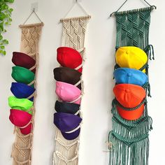 there are many hats hanging up on the wall with macrame cords attached to them