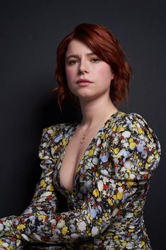 a woman with red hair wearing a floral dress