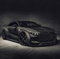 the front end of a gray sports car in a dark room with light from behind