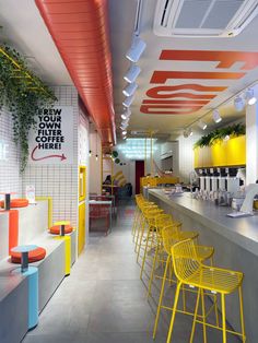 the interior of a modern restaurant with yellow chairs and neon colored accents on the walls