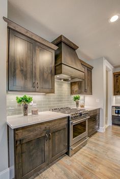 a kitchen with wooden cabinets and white counter tops, wood flooring and stainless steel appliances