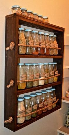 a shelf filled with lots of different types of spices on top of wooden shelves next to a wall