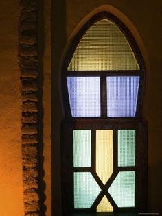 a stained glass window in the corner of a building with a candle lit up next to it