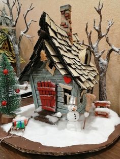 a small wooden house with snow on the ground and trees in front of it that have been made out of cardboard