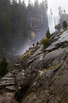 two people walking up some steps near a waterfall