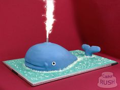 a birthday cake with a blue whale on it's side and sparklers in the air