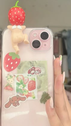 someone holding up their phone case with stickers on it and an apple in the back