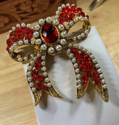 A Beautiful & unique Bow Brooch red color with Cream pearls. Antique gold plated , Has a Vintage look. Size is L71mm x W60mm x TH20mm. this item is one of our One of a kind pieces. Elegant Red Brooches As Gifts, Handmade Elegant Red Brooches, Holiday Red Brooch Jewelry, Handmade Vintage Red Brooches, Red Brooch, 50th Anniversary Decorations, Ornate Red Jewelry Brooch, Christmas Brooches, Wedding Brooches