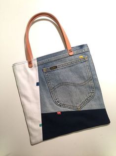 a handbag made out of jeans and leather handles on a white table with an orange handle