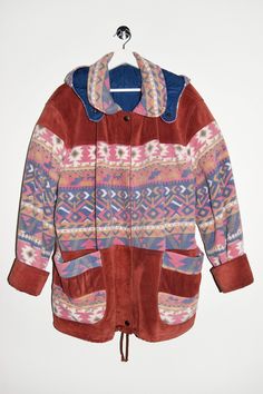 a jacket hanging on a hanger with a white wall in the background and an orange, pink, blue, and purple pattern