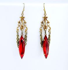 "These beautiful handmade earrings feature dramatic siam ruby navette crystals accented with two chain loops in the backdrop. Paired with highly detailed antique brass filigree for an elegant Gothic design. Earrings measure approximately 2 3/16\" long end to end (from top of ear wire to base of crystal). Solid antique brass french hook wires are beautifully aged and are lead and nickel free. Crystals are set in hand antiqued solid brass settings. All jewelry arrives in a complimentary decorative Opulent Earrings, Ruby Aesthetic, Vampire Jewelry, Victorian Earrings, Brass Filigree, Fantasy Ideas, Gothic Design, Elegant Gothic, Gothic Accessories