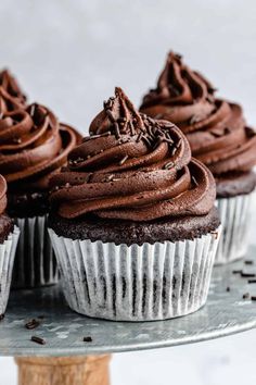 three chocolate cupcakes sitting on top of a cake plate