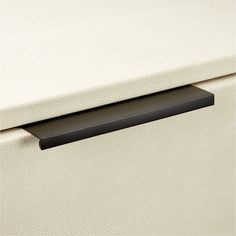 a close up of a drawer handle on a white leather cabinet with black metal handles