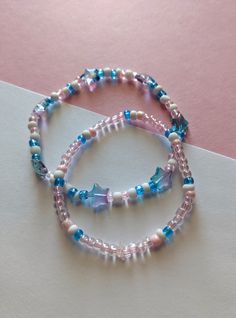 two beaded bracelets with blue and pink beads on a white tablecloth background