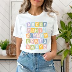 a woman wearing a white t - shirt with colorful letters on the front and back