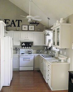 a kitchen with white cabinets and wood flooring next to a refrigerator freezer oven