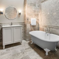 a white bath tub sitting next to a sink in a bathroom under a round mirror