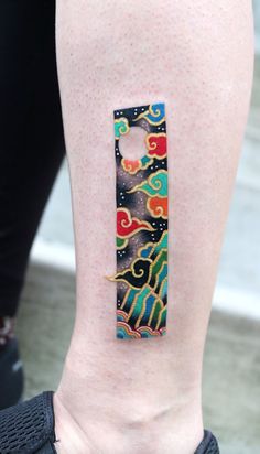 a woman's leg with a colorful tattoo design on the back of her thigh