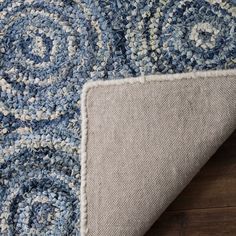 a blue and white area rug on top of a wooden floor next to a piece of wood