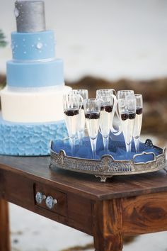 there is a tray with wine glasses on it and a cake in the back ground