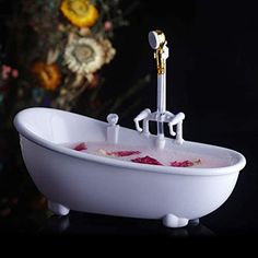 a white bath tub filled with pink liquid and two gold faucets sitting on top of it