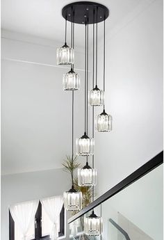 a glass chandelier hanging from the ceiling in a room with stairs and windows