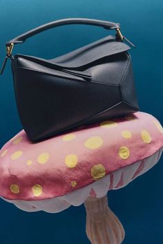 a black handbag sitting on top of a mushroom shaped object in the water with polka dots