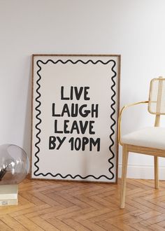 a black and white poster sitting on top of a wooden floor next to a chair