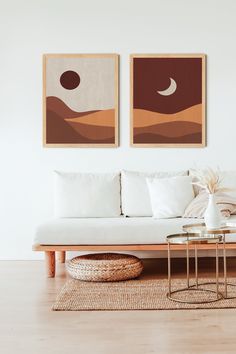 two paintings hang on the wall above a couch in a room with wood flooring