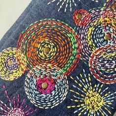 a close up of a piece of cloth with colorful designs on it and buttons in the center