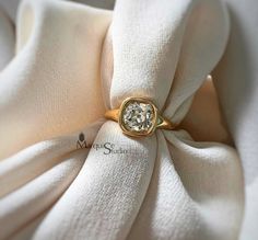 a gold ring with a diamond on it sitting on top of a white cloth covered napkin