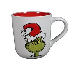 a white and red coffee mug with the grin face on it's side, wearing a santa hat