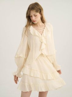 This product brings a touch of vintage-inspired charm, showcasing ruffled details that impart a romantic, nostalgic feel. The blouse stands out with its cascading ruffles around the neckline and down the front, paired with a lace-up detail that offers a subtle hint of allure. Its puffed sleeves with gathered cuffs add a voluminous, soft structure, encapsulating a blend of classic style and modern femininity. - This blouse features an intricate ruffle design that frames the face and adds a dimensional aesthetic to the garment- The lace-up front detail provides a customizable fit and lends a bohemian elegance to the blouse- Its puffed sleeves with elasticized cuffs create a blouson effect that’s both flattering and on-trend- A subtle, handcrafted medal decoration on the lower righ Chic Ruffled Blouse For Spring, Ruffled Collar Blouse With Ruffle Hem For Daywear, Feminine Spring Blouse With Ruffles, Feminine Blouse With Ruffle Hem And Ruffled Collar, Feminine Ruffled Blouse For Brunch, Feminine Ruffled Blouse For Daywear, Chic Ruffled Blouse For Brunch, Cottagecore Ruffle Blouse For Summer, Summer Cottagecore Blouse With Ruffles