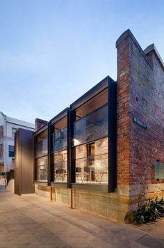 an old brick building with glass windows on the outside