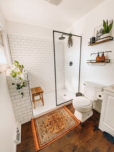 a bathroom with a rug, toilet and shower in it's centerpieces