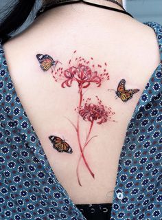 a woman's back with butterflies and flowers on her left shoulder, which is covered in red ink