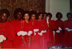 a group of women in red dresses standing next to each other