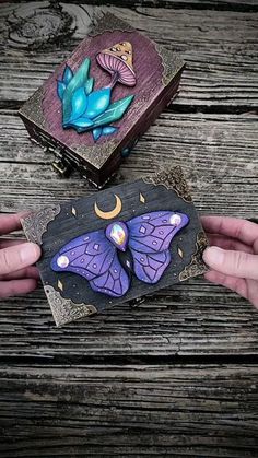 two hands are holding some paper with butterflies and moon designs on them, while another hand is holding something in the other hand