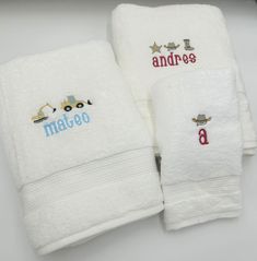 three white towels with embroidered name and construction vehicles on them, sitting next to each other