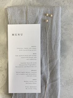 a menu card sitting on top of a piece of paper next to a string of flowers