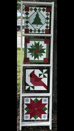 three quilts are hanging on the side of a tree