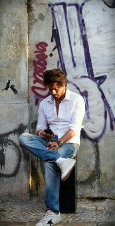 a man sitting on top of a pole next to graffiti